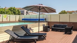 Un espace aménagé au bord de la piscine, avec des chaises longues, une table et un parasol.