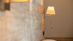 Una lámpara de pared con pantalla rectangular, una pared de madera con textura y una mesita de noche de madera.