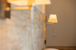 Una lámpara de pared con pantalla rectangular, una pared de madera con textura y una mesita de noche de madera.