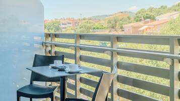 A balcony with a table and chairs, overlooking a residential area with houses and greenery.
