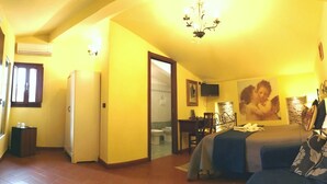 Ein Hotelzimmer mit einem Bett, einem Schreibtisch, einem Stuhl, einem kleinen Schrank und einem durch eine offene Tür sichtbaren Badezimmer.
