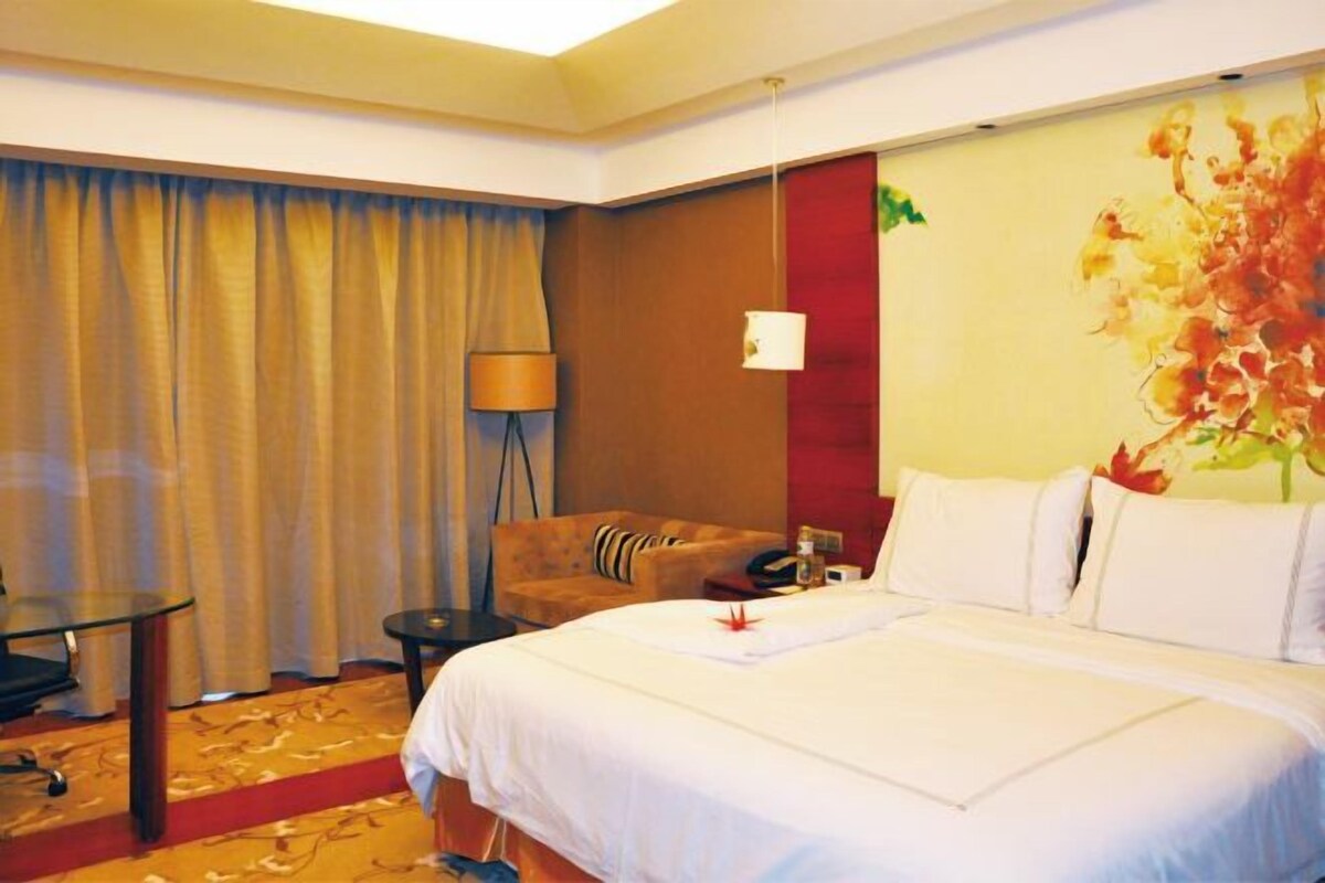 Ein Hotelzimmer mit einem großen Bett, einem Schreibtisch, einem Stuhl und einer Lampe.