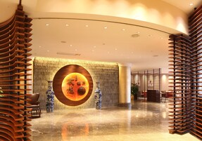 Un lobby moderno con un diseño de pared circular, una recepción y un área de descanso.