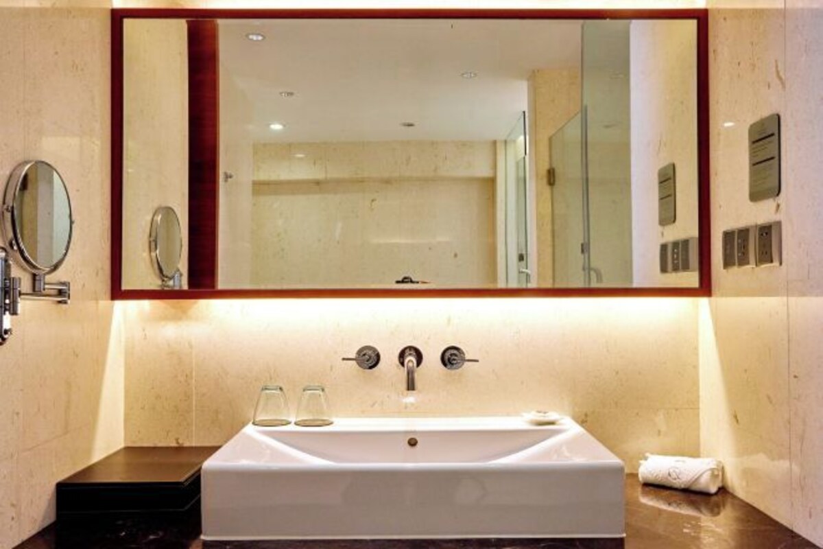 A bathroom with a large mirror, a white sink, and a towel on the counter.