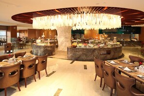 Ein modernes Restaurant mit einer zentralen Marmorinsel, Sitzgelegenheiten darumherum und einer großen Kronleuchter.