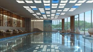 Een modern binnenzwembad met betegelde vloer en in het plafond geïntegreerde verlichting.