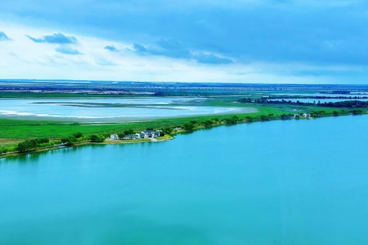 A river with a small island containing a few buildings.
