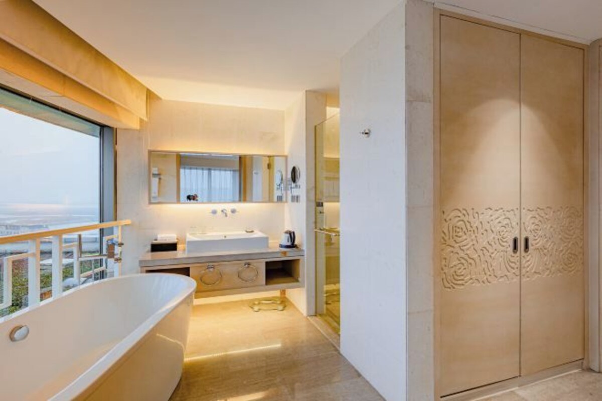 A modern bathroom with a freestanding bathtub, a vanity with a mirror, and a large wardrobe.