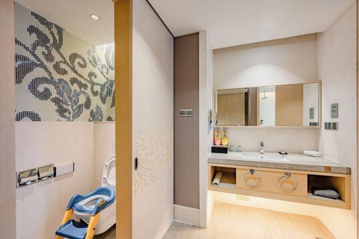 A modern bathroom with a toilet, a sink with a mirror, and a shower area.