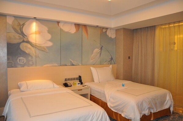 Une chambre d’hôtel avec deux lits, une table de chevet avec un téléphone et une bouteille, et un grand tableau représentant des fleurs accroché au mur.
