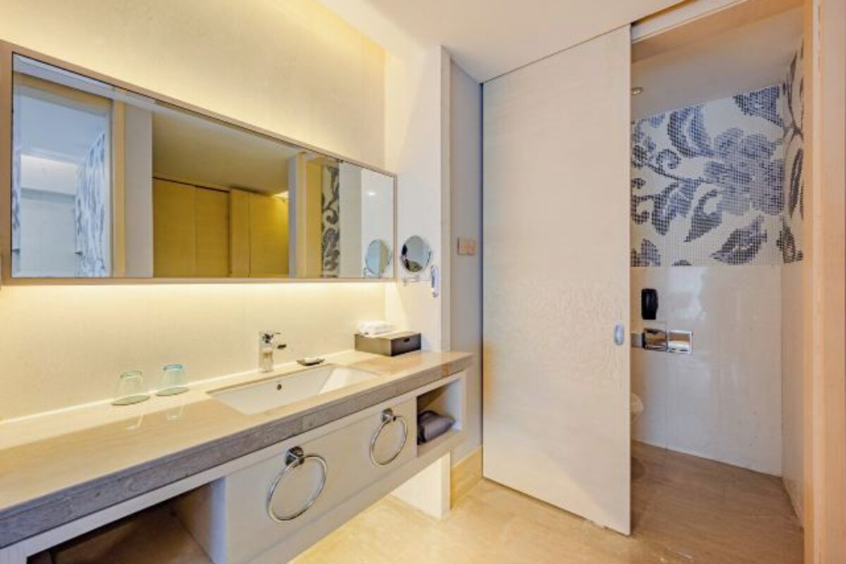 A modern bathroom with a large mirror, a sink, and a shower area.