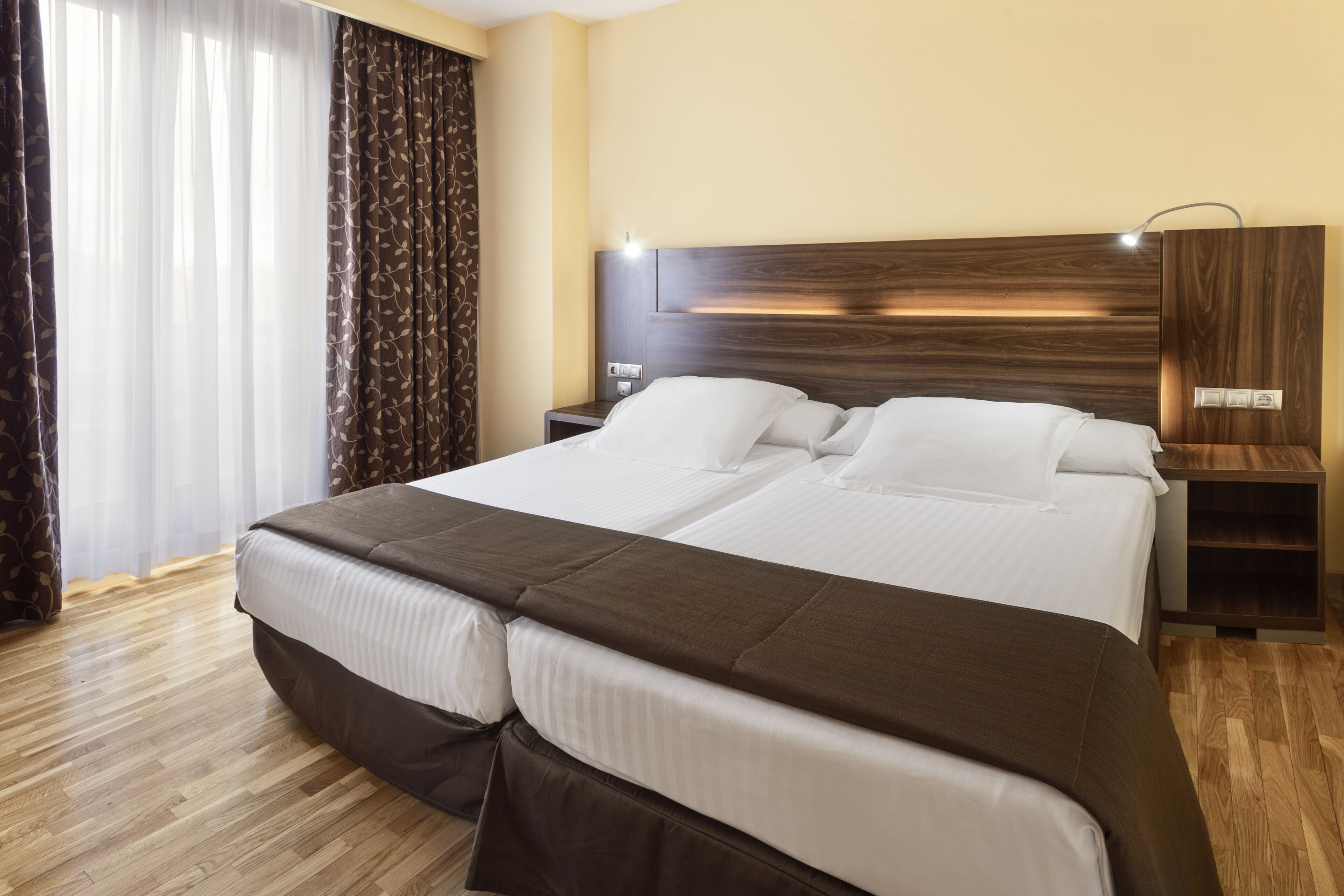 A double bed with a wooden headboard, a nightstand, and a bedside lamp.