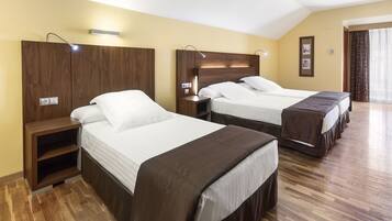 Habitación de hotel con dos camas, cabeceros de madera, mesitas de noche y un ventanal con cortinas.
