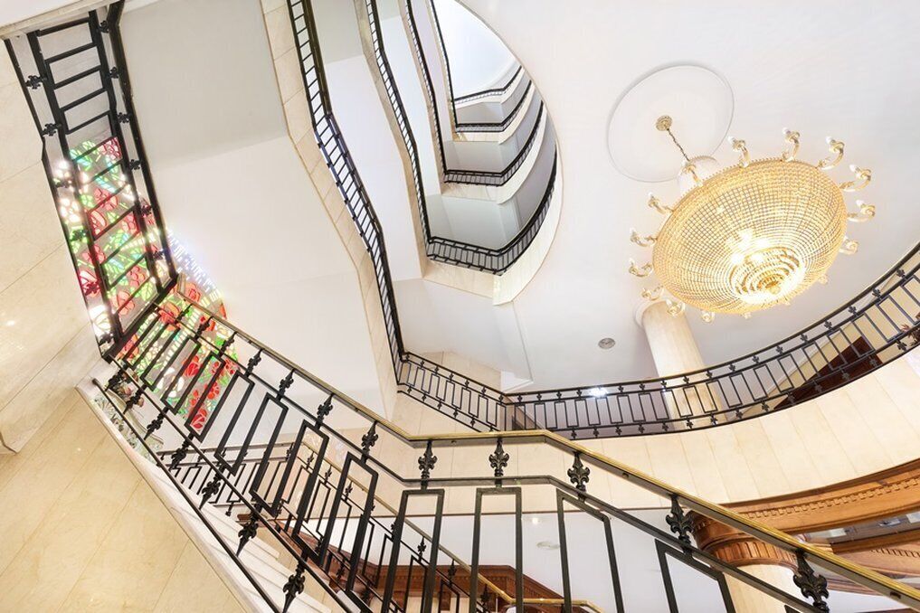 A multi-level interior with a spiral staircase, a decorative chandelier, and a patterned wall.