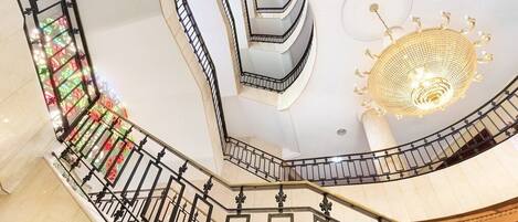 A multi-level interior with a spiral staircase, a decorative chandelier, and a patterned wall.