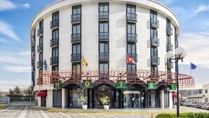 Un hotel con fachada curva, varios balcones y banderas.