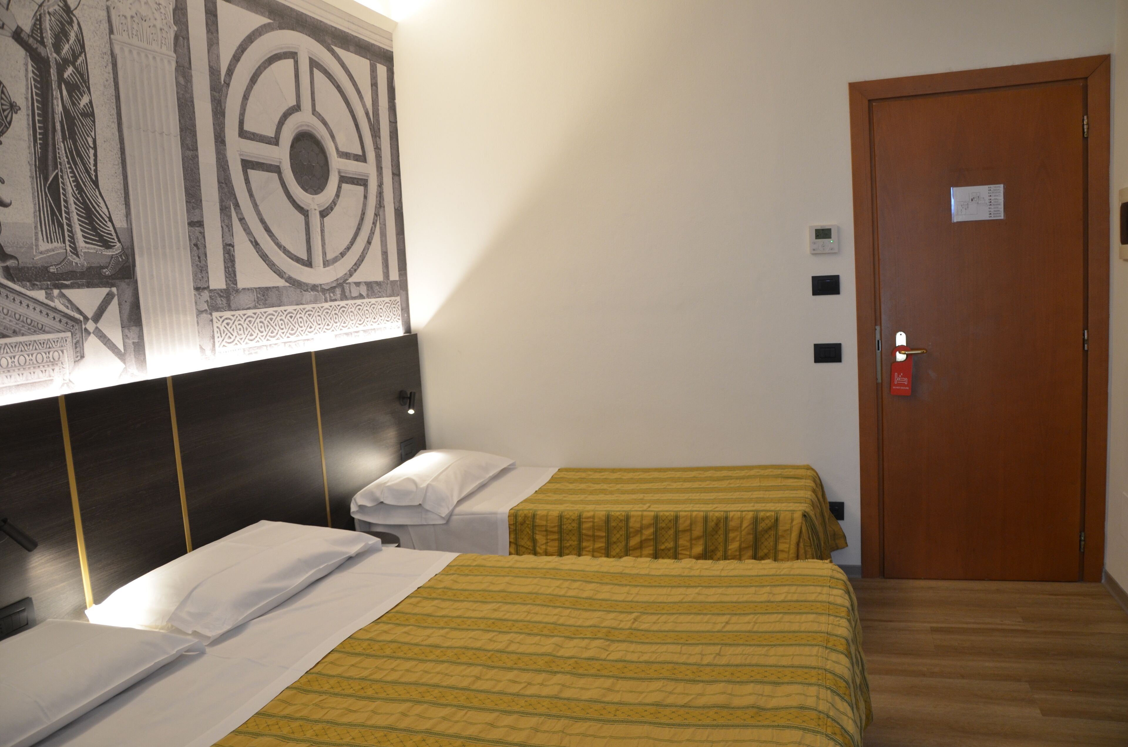 Une chambre d’hôtel avec deux lits, une porte en bois et une œuvre d’art accrochée au mur.