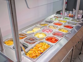 Un buffet con diversi cibi esposti in contenitori separati.