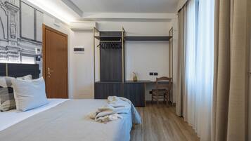Habitación de hotel con cama, escritorio y silla. Se observa un armario y una ventana con cortinas.