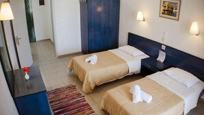 Quarto de hotel com duas camas, uma escrivaninha, um guarda-roupa e um tapete pequeno.