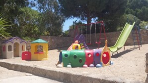 Uma área de recreação infantil com um trem, um escorrega e casinhas.
