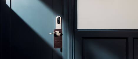 Una puerta con un cerrojo de seguridad y una placa con el número de habitación.