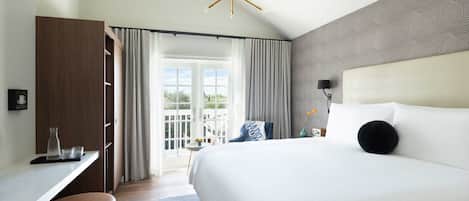 A modern hotel room with a large bed, a desk, and a view of the outdoors.