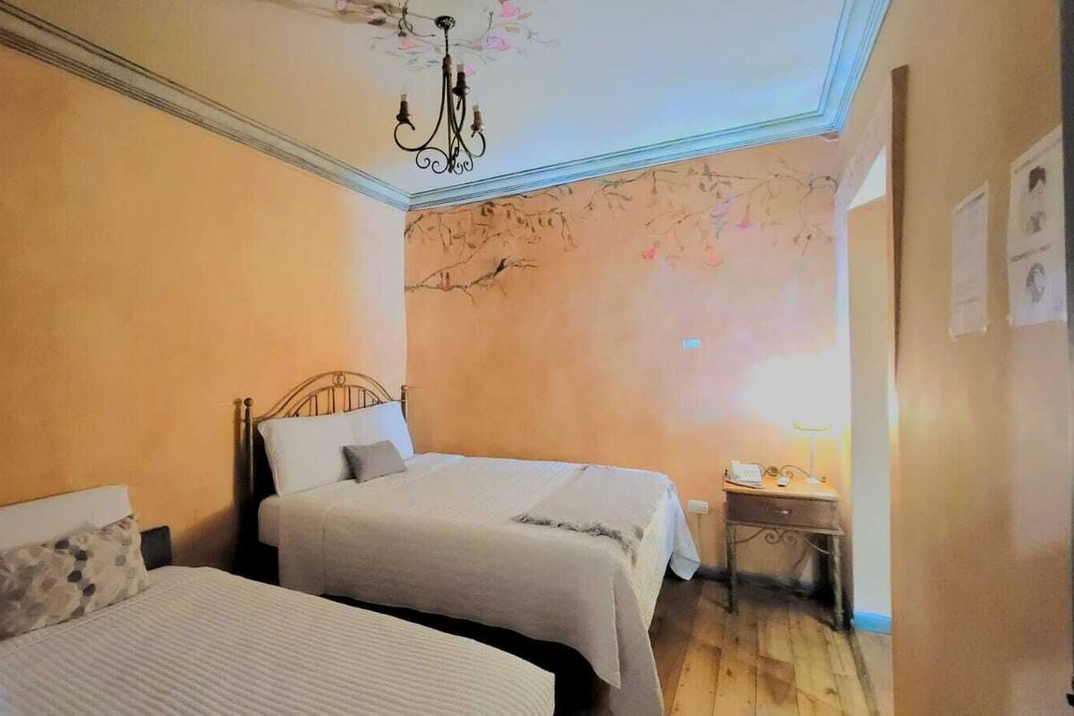 A room with two beds, a desk, and a chandelier.
