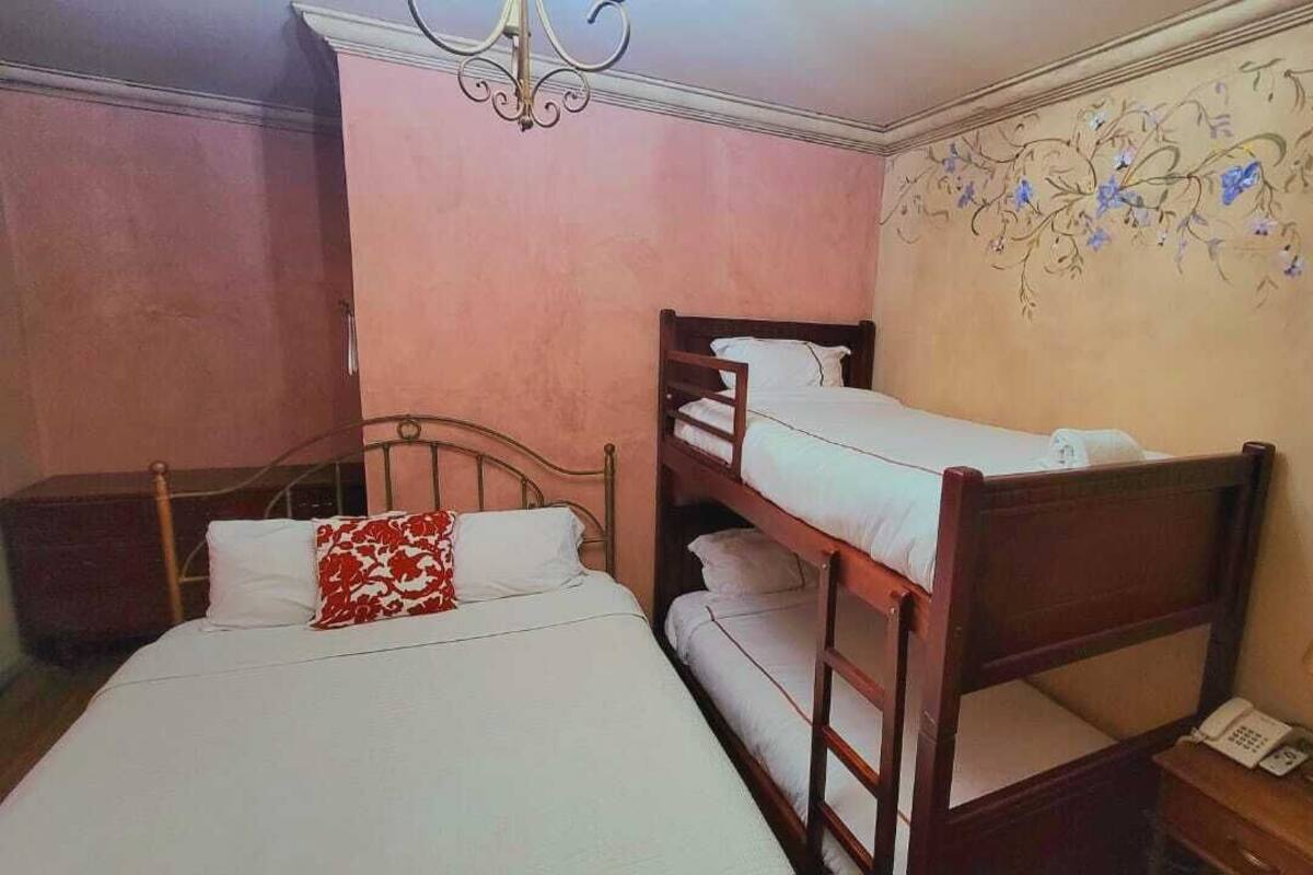 A bedroom with bunk beds, a bedside table with a lamp, and a wall with floral wallpaper.