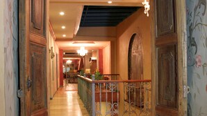 Un pasillo con suelo de madera, puertas ornamentadas y un techo decorativo.