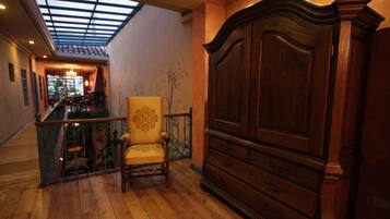 A room with a wooden floor, a large wooden cabinet, a chair, and a glass ceiling.
