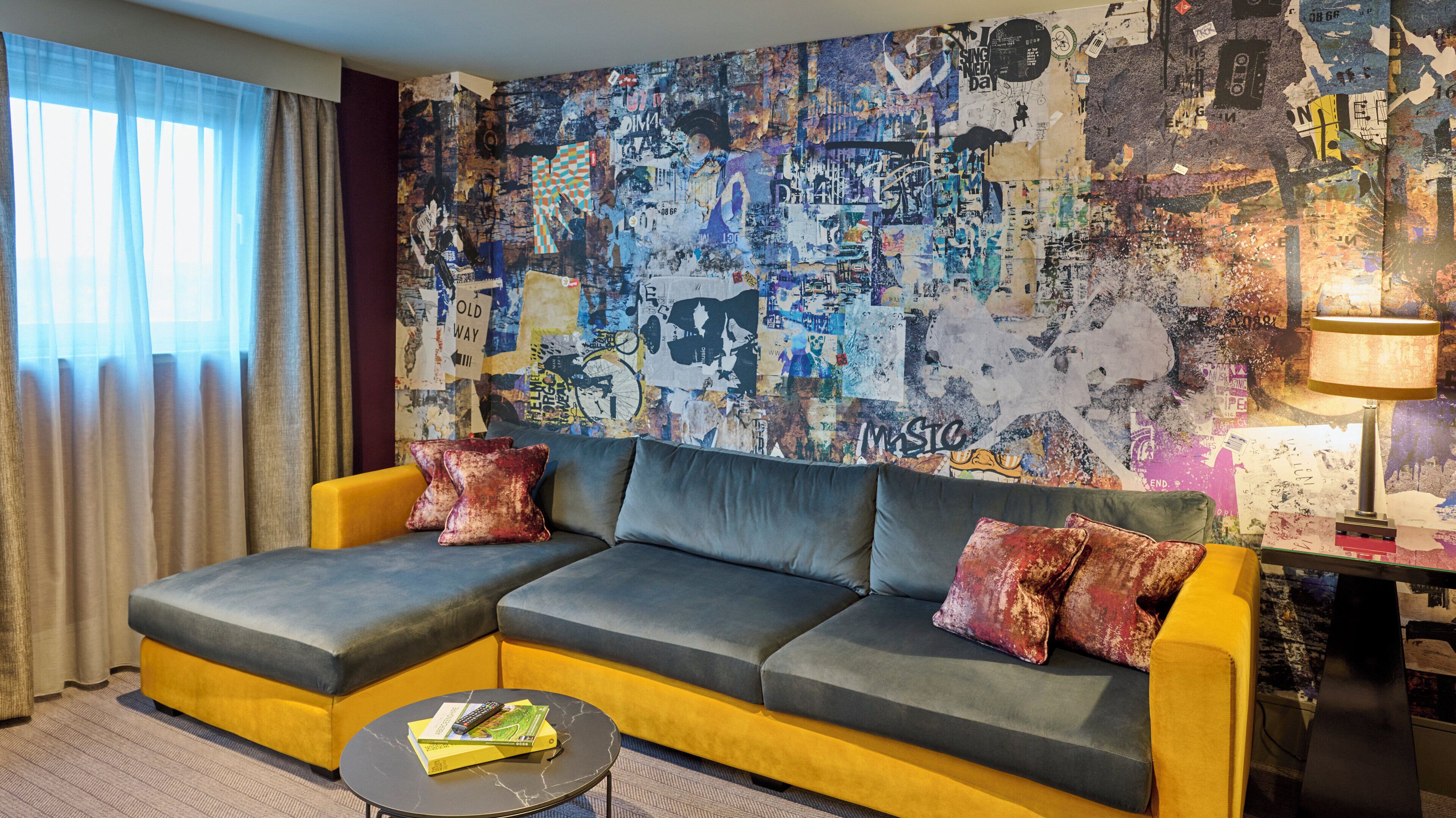 Una sala de estar moderna con un sofá seccional, una mesa de centro y una pared decorada con arte abstracto.