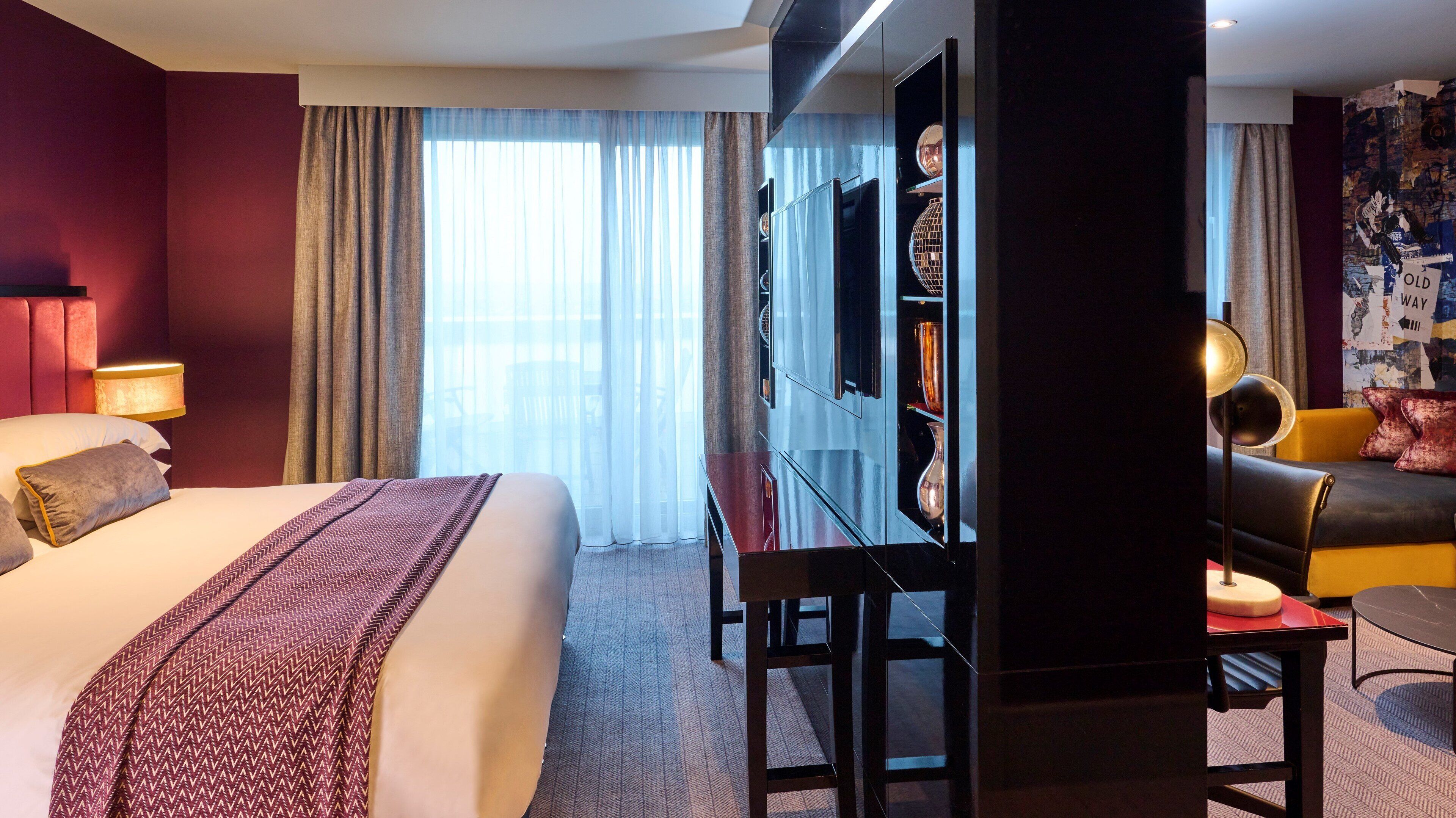 Una habitación de hotel con una cama grande, un escritorio con silla, televisión y sofá.