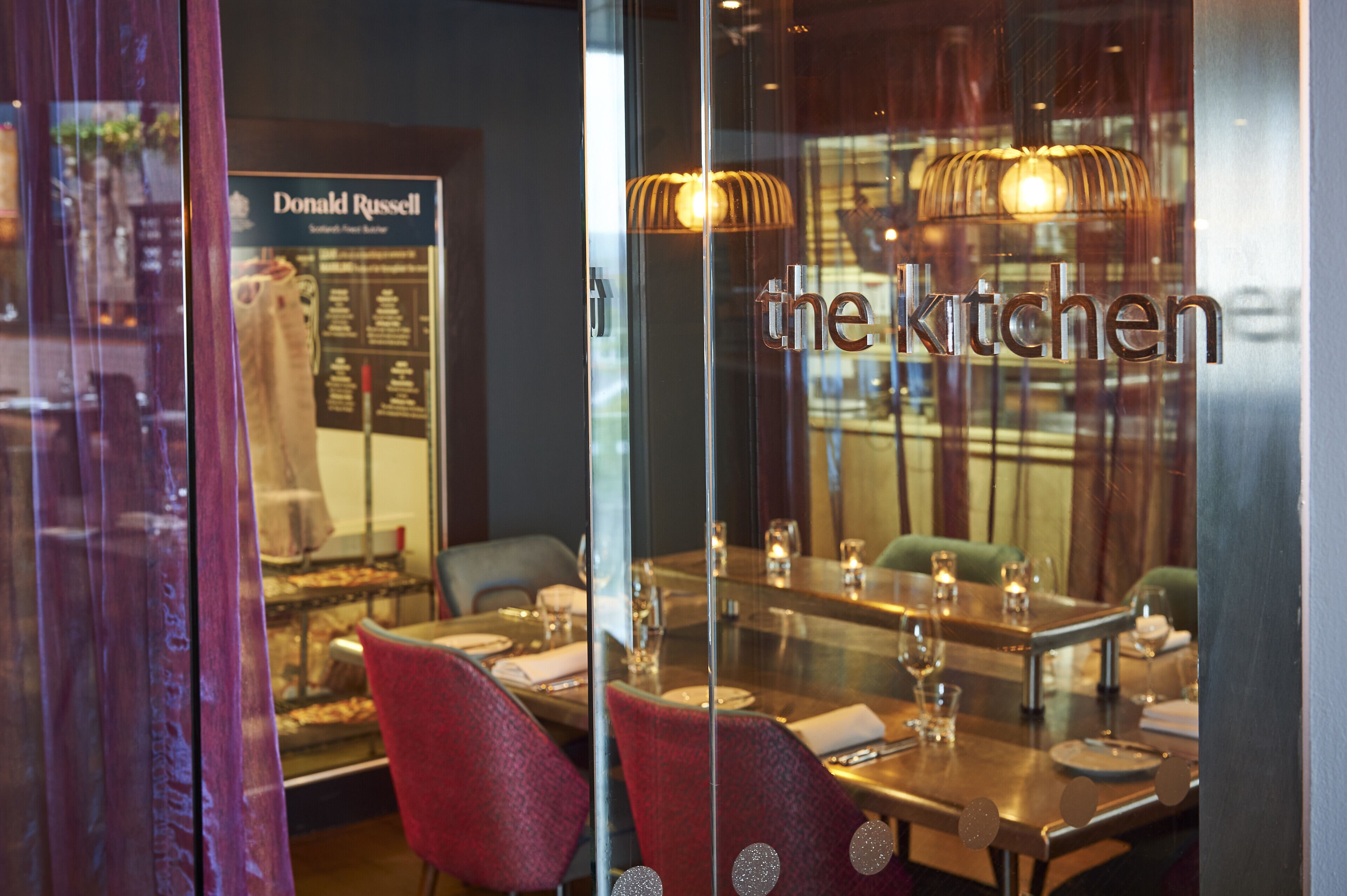 A restaurant interior with a glass partition displaying the name 'the kitchen'.