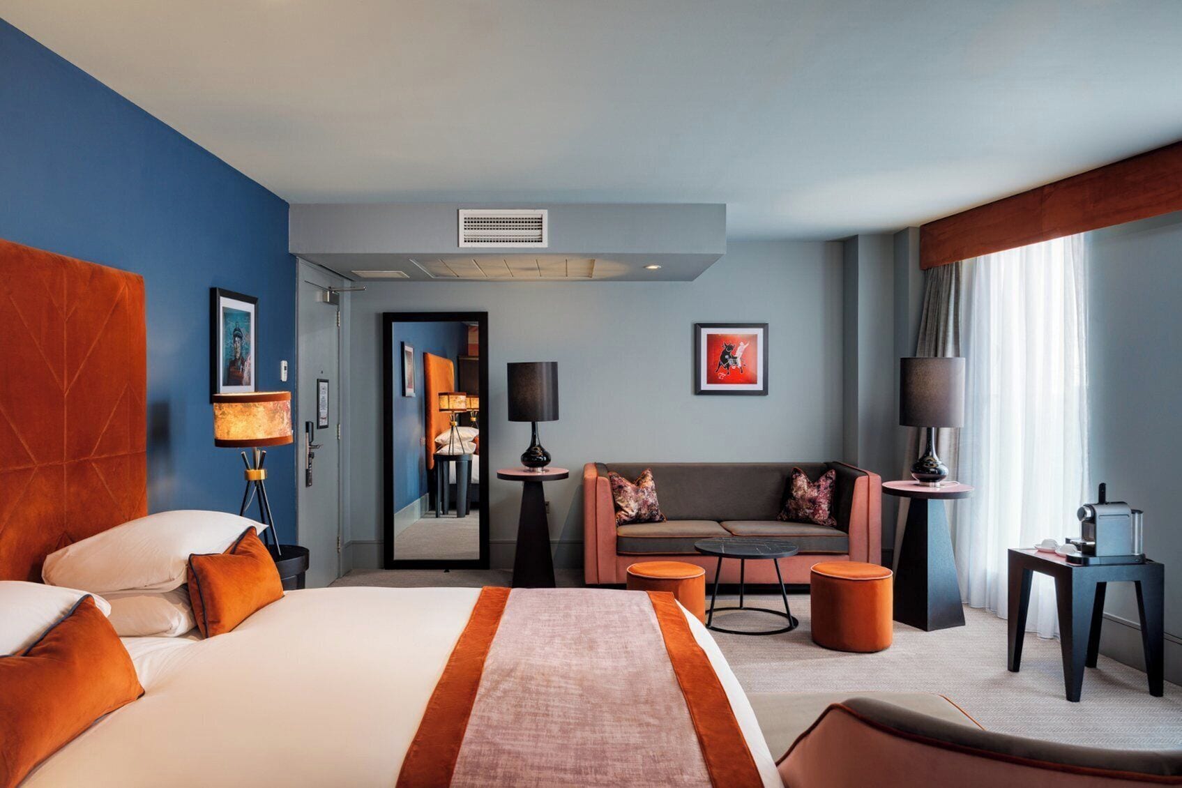 Une chambre d’hôtel avec un grand lit, un canapé, une table basse et un bureau avec une lampe.