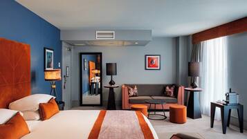 Une chambre d’hôtel avec un grand lit, un canapé, une table basse et un bureau avec une lampe.