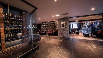 A bar area with a wine rack, seating, and a stone wall.