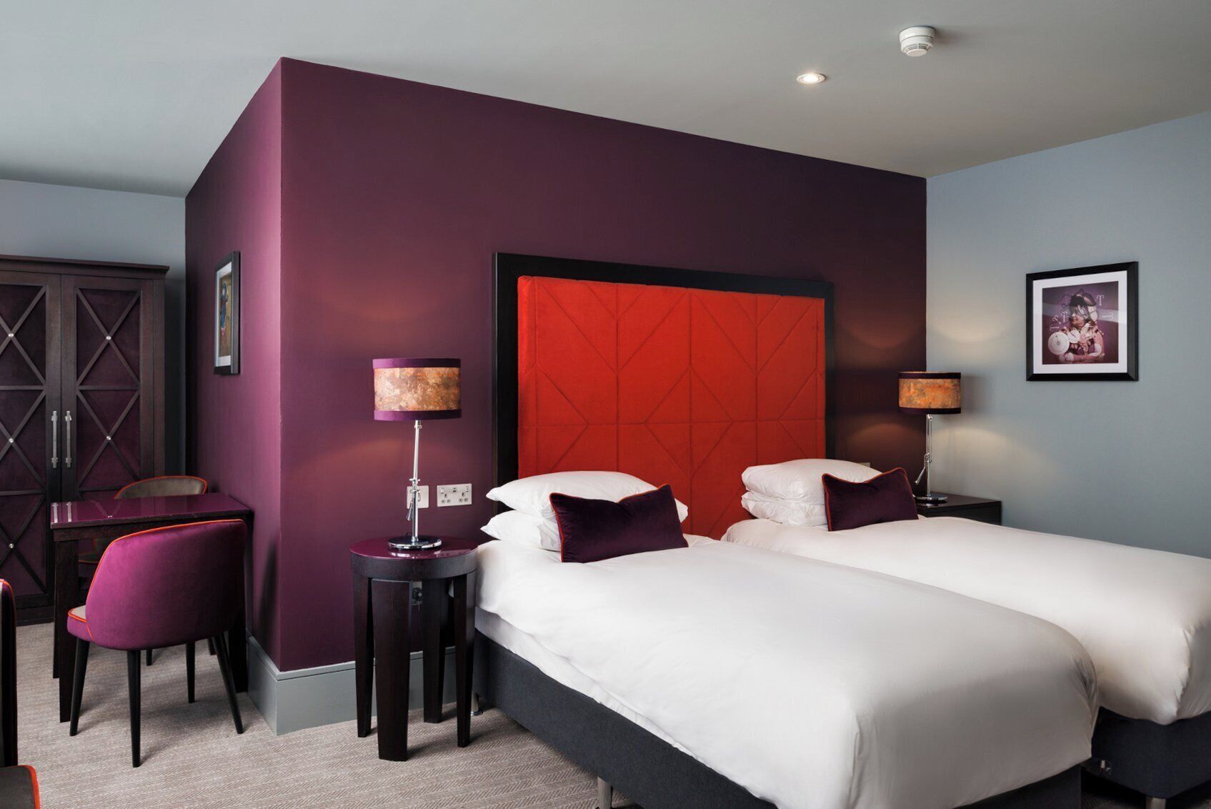 A hotel room with two beds, a desk, and a chair.