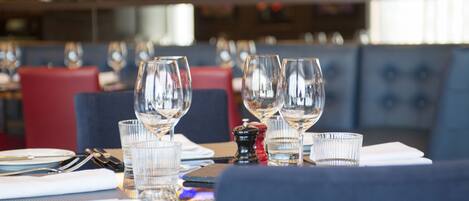 A restaurant setting with tables set for dining, including plates, glasses, and cutlery.