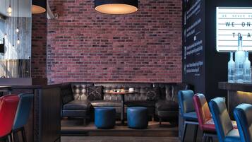 A bar area with a brick wall, leather seating, and pendant lighting.