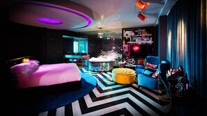 A modern, stylish room with a bed, a round table, and a bar area.