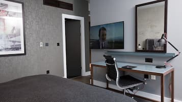 A modern hotel room with a large bed, a desk with a chair, a television, and a large mirror.