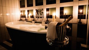 A bathtub with a champagne bottle and a towel.