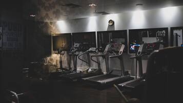 Un gimnasio con cintas de correr y equipo de ejercicio.