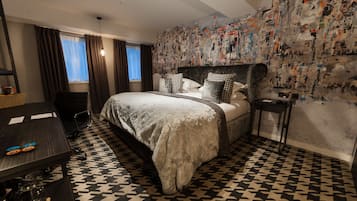 Une chambre d’hôtel avec un grand lit, un bureau avec une chaise et un mur recouvert d’affiches.