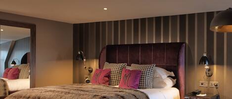 A modern bedroom with a large bed, striped wallpaper, and a mirror.
