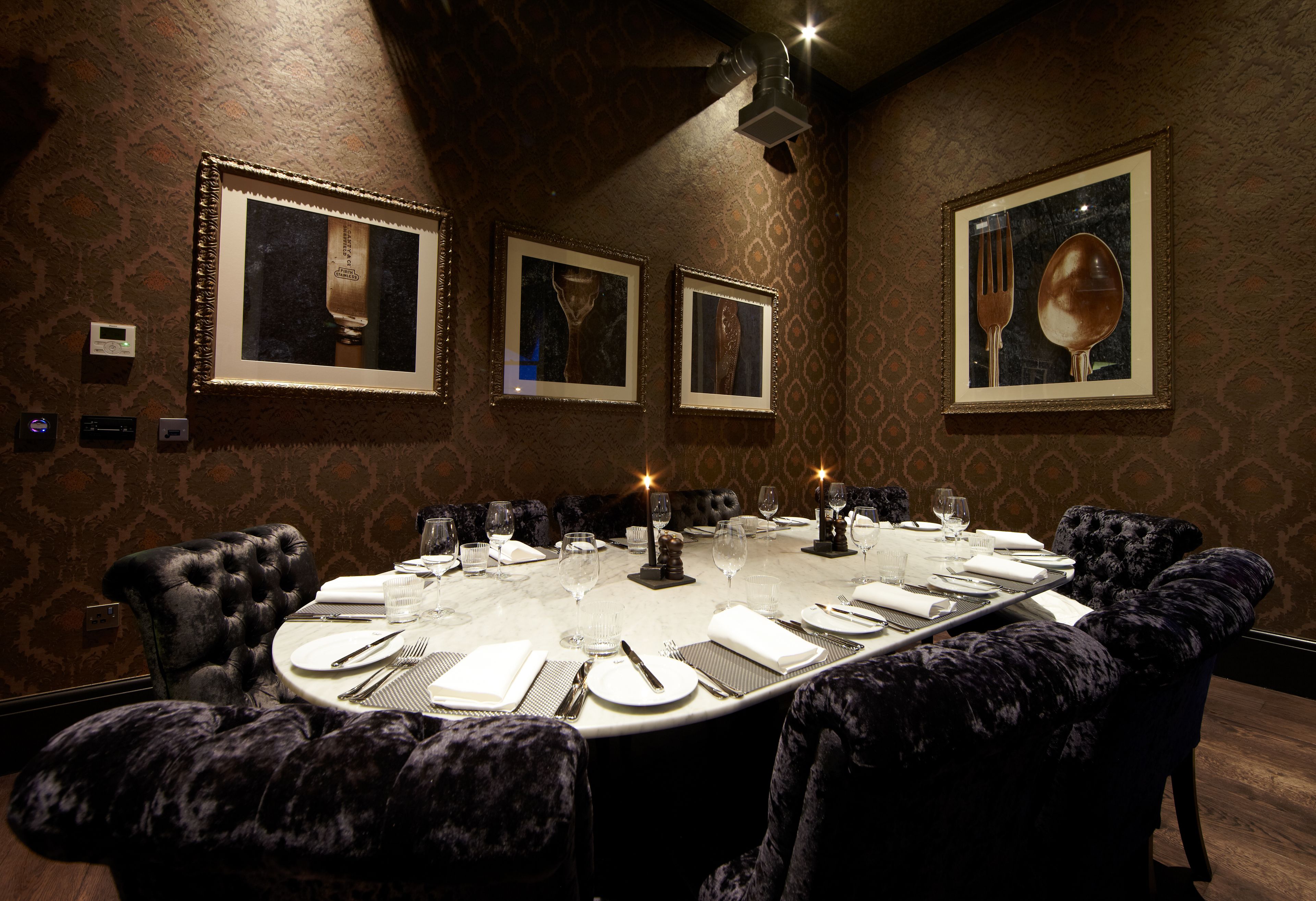 A formal dining room with a round table set for eight, surrounded by plush upholstered chairs.