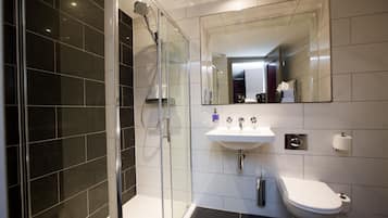 A modern bathroom with a glass shower enclosure, a white sink, and a toilet.