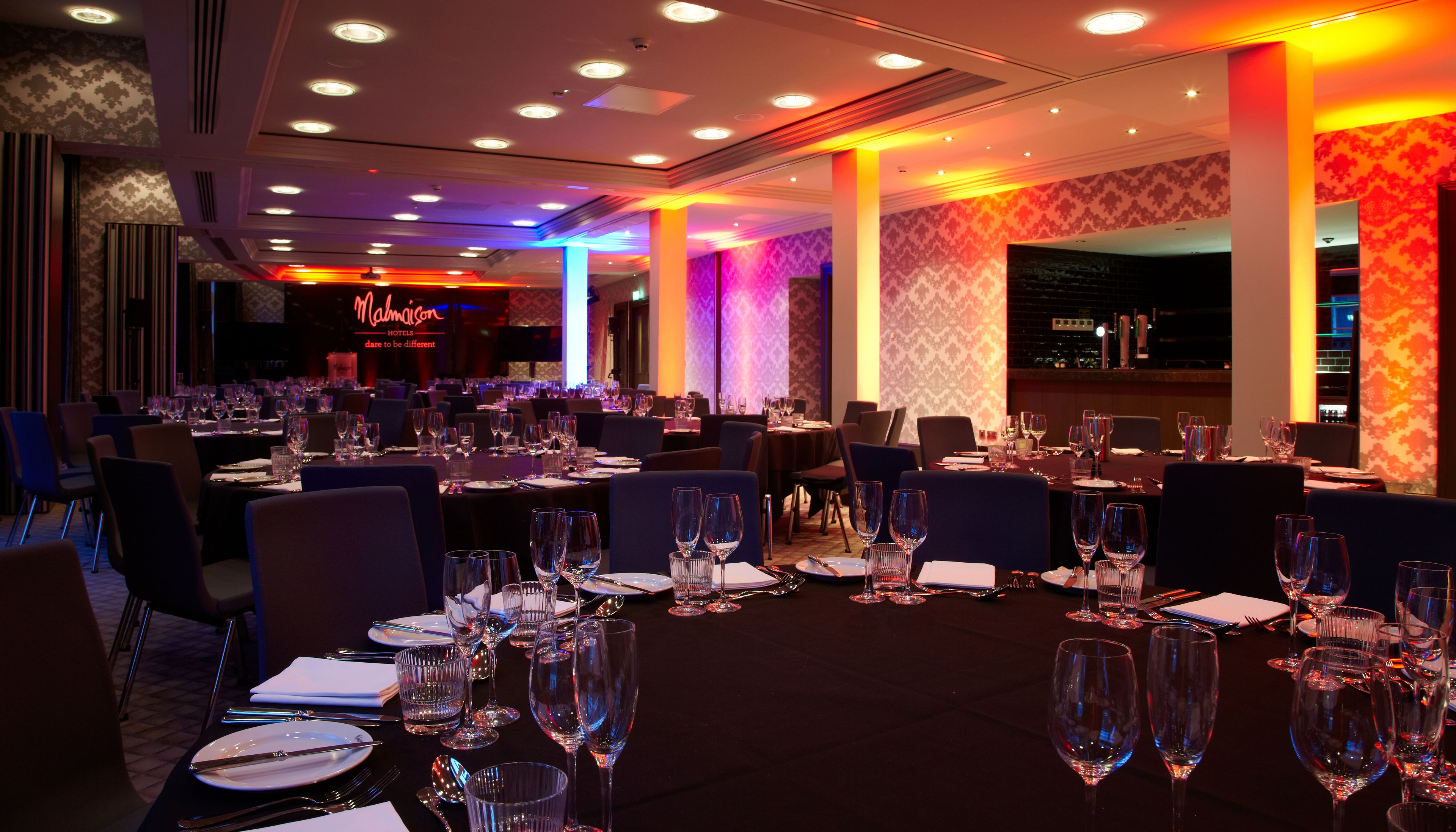 Een restaurantgedeelte van een hotel met meerdere gedekte tafels, inclusief glazen en bestek.