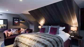 Un dormitorio moderno con una cama grande, un sofá y un escritorio con una lámpara.